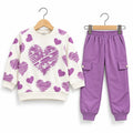 A children's two-piece outfit set featuring a cream sweatshirt with purple heart patterns and matching purple jogger pants, displayed on wooden hangers against a white background.