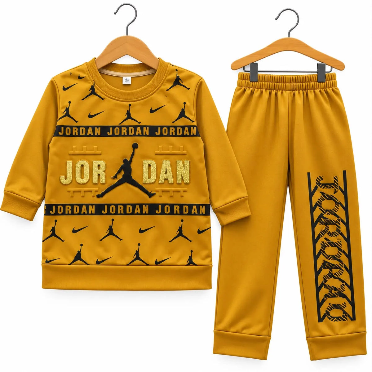 A two-piece kids' tracksuit set in mustard yellow, featuring a long-sleeve sweatshirt and matching pants on wooden hangers against a white background. The set is branded with Jordan and Nike logos and graphics.