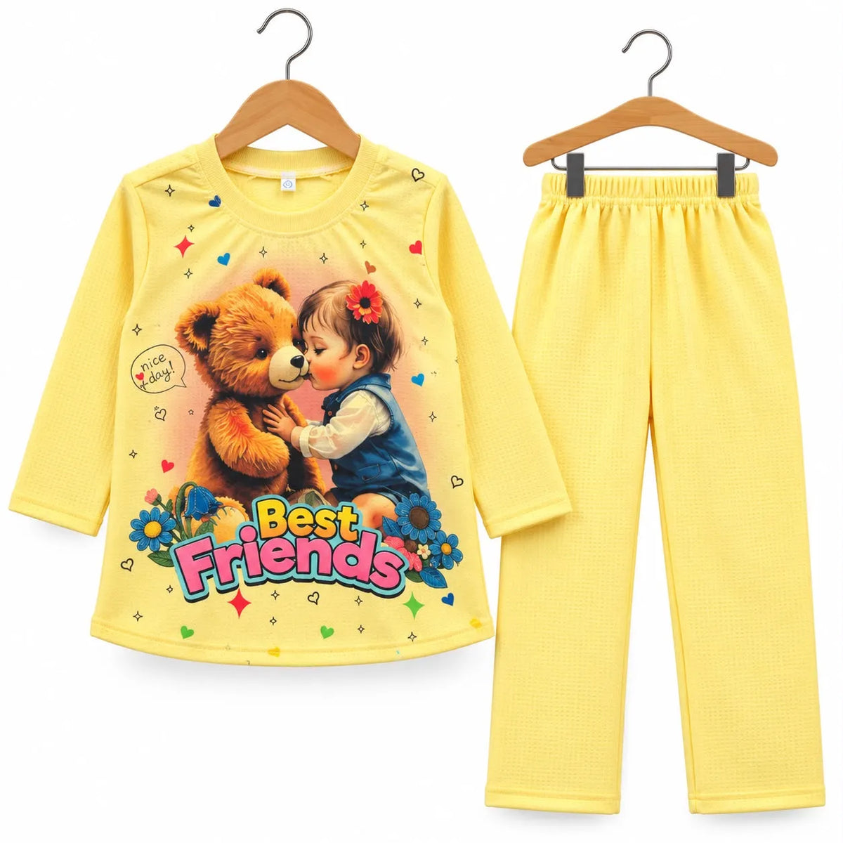 A two-piece children's pajama set consisting of a long-sleeve yellow top and matching yellow pants, displayed on wooden hangers against a white background. The top features a colorful graphic of a child hugging a teddy bear with the text 'Best Friends' and 'Happy Birthday'.