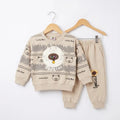 A two-piece children's sweatshirt and pants set in beige, displayed on wooden hangers against a white background. The sweatshirt features a cartoon bear graphic with the text 'Lucky Bear' and 'Special', while the pants have 'Special' printed on the leg.
