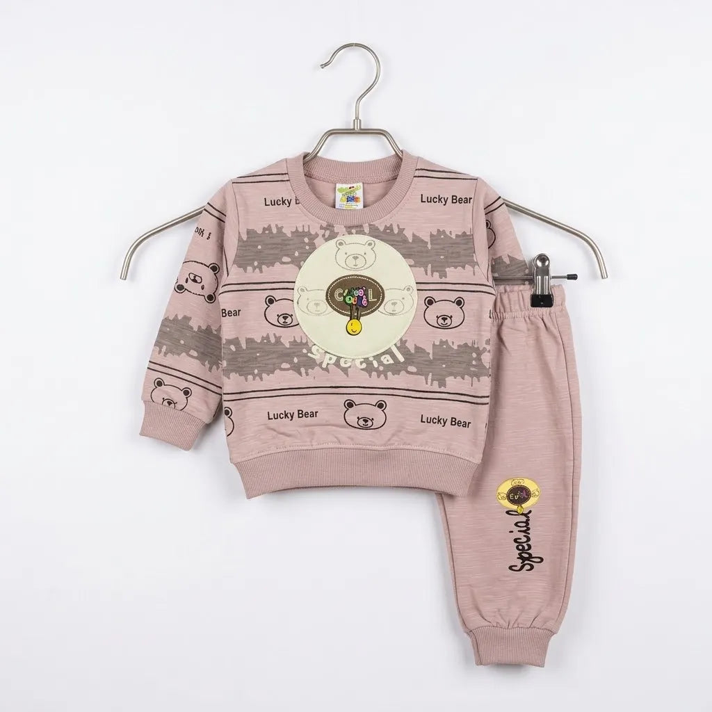 A two-piece children's clothing set consisting of a long-sleeve sweatshirt and matching pants, displayed on a metal hanger against a plain white background. The set is a dusty rose pink color with cartoon bear graphics, 'Lucky Bear' text, and a central circular graphic on the sweatshirt.
